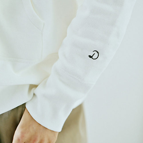 左の袖に配したロゴ刺しゅうは、白いボディになじむグレーを選択。